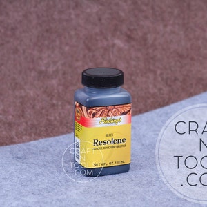 K&ouml;nnte beinhalten: Eine 118 ml Flasche schwarzer Fiebing's Resolene Lederfinish. Die Flasche hat ein schwarzes Etikett mit wei&szlig;em Text, auf dem "BLACK Resolene PROTECTIVE EPOXY FINISH FOR LEATHER NET 4 FL OZ 118 ml" steht.