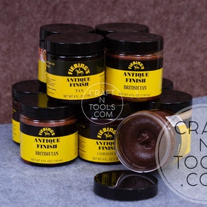 May include: Multiple jars of Fiebing's Antique Finish leather dye in various colors, including Tan, British Tan, and Cordova. The jars are stacked on a gray surface. The text "CRAFT N TOOLS .COM" is visible in the background.