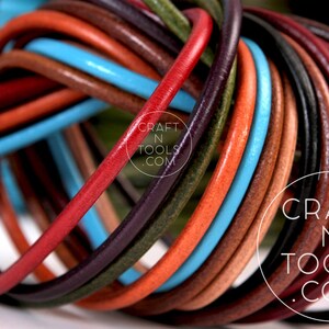 May include: A close-up of a variety of leather cords in different colors, including red, orange, brown, blue, and green. The cords are twisted together in a knot, creating a colorful and textured pattern. The text "CRAFT N TOOLS .COM" is visible on the cords.