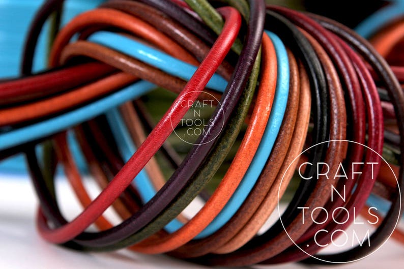 May include: A close-up of a variety of leather cords in different colors, including red, orange, brown, blue, and green. The cords are twisted together in a knot, creating a colorful and textured pattern. The text "CRAFT N TOOLS .COM" is visible on the cords.