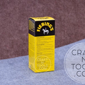 May include: A yellow and black box of Fiebing's Leather Dye. The box has a picture of a person riding a horse. The text on the box reads "Fiebing's" and "Leather Dye".