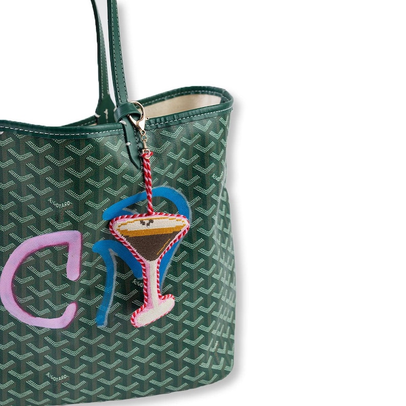 Green patterned handbag with a cocktail charm on a white background