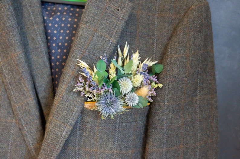 May include: A brown tweed jacket with a pocket square made of dried flowers and greenery.