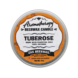 May include: A round, silver tin with an orange label. The label reads "Aromatherapy Beeswax Candle", "TUBEROSE", "Made with Essential Oils 100% Natural", "Zax Beeswax", "100% Pure & Natural Beeswax Candles", "Veteran Owned and Operated", and "Net Wt. 4 oz."