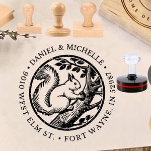 Puede incluir: Una colección de sellos de madera, incluyendo un sello redondo con un diseño de ardilla y el texto "Daniel & Michelle". Otros sellos tienen mangos de madera y un mango de acrílico transparente. También hay un círculo amarillo con el número 1.