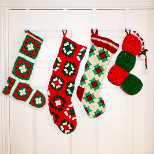 May include: Four handmade crochet Christmas stockings hanging in a row. The first is white with red and green granny squares. The second is red with green and white squares. The third is cream with red and green squares. The fourth is red and green.