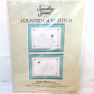 May include: A packaged cross-stitch kit titled "Something Special" featuring two framed swan pictures. The finished size is 7.5 inches each, matted to 8.5 x 6.5 inches. The kit includes Aida cloth, cotton floss, a graph, needle, and instructions.