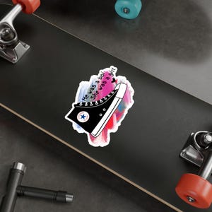 May include: A black and white illustration of a high-top sneaker with the text "He was a boy, she was a girl" on a pink, blue, and purple watercolor background.