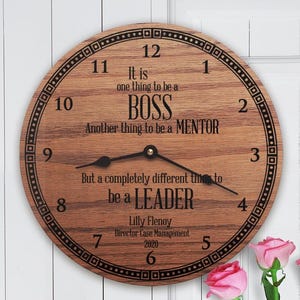 May include: A round wooden clock with black numerals and hands. The clock face has the text "It is one thing to be a BOSS, another thing to be a MENTOR, but a completely different thing to be a LEADER."