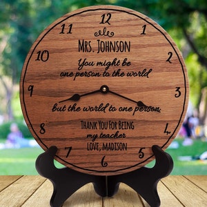 May include: A wooden clock with a quote that reads "You might be one person to the world but the world to one person". The clock is personalised with the name "MRS. JOHNSON" and the message "Thank you for being my teacher Love, Madison".