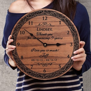 May include: A wooden clock with a black face and black hands. The clock has a decorative border and the text "Lindsey, Thank you for an amazing 5 years I love you so much! Jeff 08/10/12 - 08/10/17" is engraved on the face.
