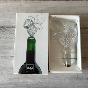 May include: A clear glass bottle stopper with a crystal raspberry design and a green leaf. The stopper is in its original box, which is white with the word "Mikasa" printed on it.
