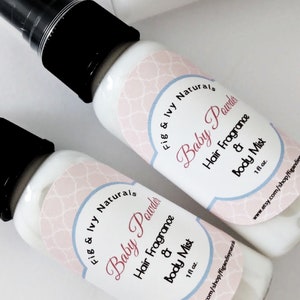 May include: Two white spray bottles with black caps, labeled "Baby Powder Hair Fragrance & Body Mist." The labels have a pink and blue design with the brand name "Fig & Ivy Naturals." Each bottle contains 1 fl oz of product.