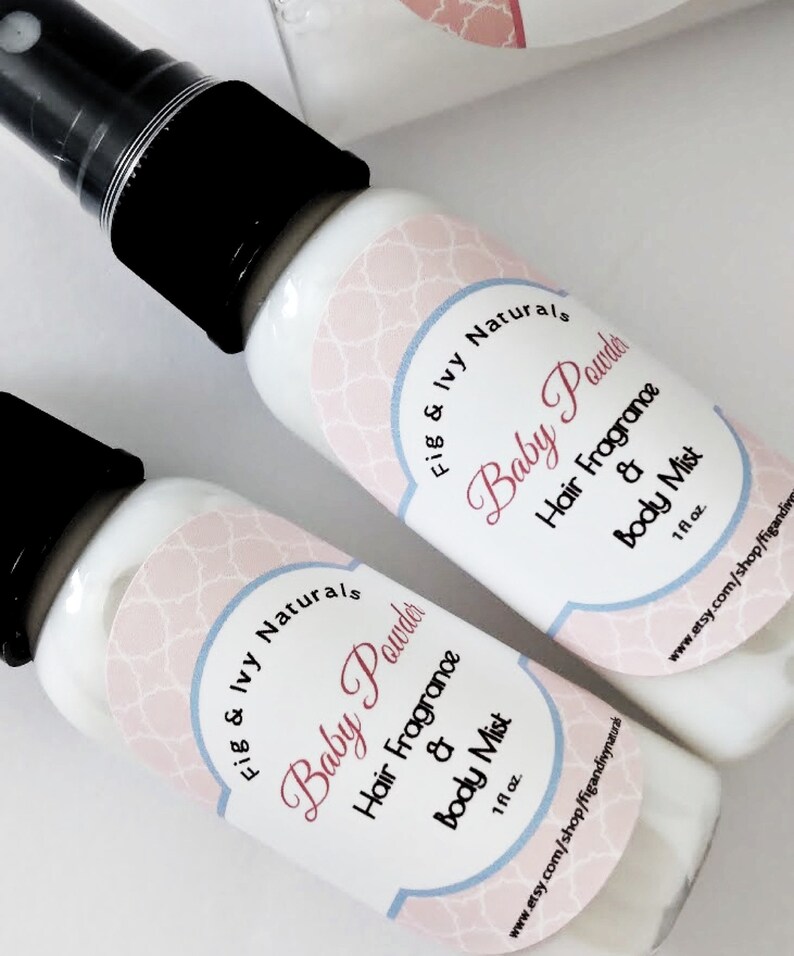 May include: Two white spray bottles with black caps, labeled "Baby Powder Hair Fragrance & Body Mist." The labels have a pink and blue design with the brand name "Fig & Ivy Naturals." Each bottle contains 1 fl oz of product.