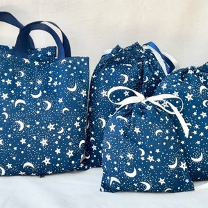 May include: Set of five blue fabric bags with a white moon and star pattern. The bags have white drawstrings and are ideal for gift wrapping or storage.