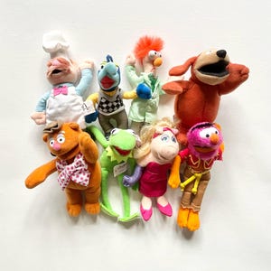 May include: A selection of plush Muppet Show character dolls, including Kermit the Frog, Miss Piggy, Fozzie Bear, and Animal. The dolls are brightly coloured and feature detailed facial expressions and clothing, ideal for fans of the classic television show.