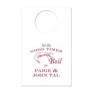 Könnte beinhalten: Weißer Türanhänger mit rundem Ausschnitt oben. Roter Text mit "let the GOOD TIMES Boil" und einer Garnelen-Illustration. Darunter steht "for PAIGE & JOHN TAL".