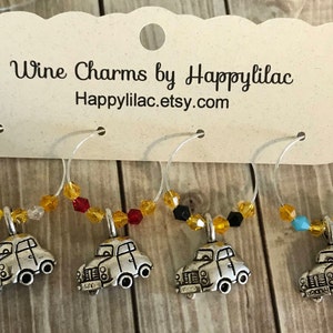 May include: Set of four wine charms with silver car pendants and colorful beads. The charms hang from silver hoops and are attached to a white card with the text "Wine Charms by Happylilac" and a website address.
