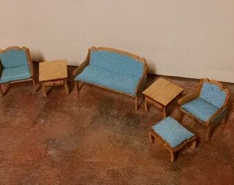 May include: Miniature dollhouse furniture set featuring a loveseat, two armchairs, two side tables, and an ottoman. The wooden frames have a light finish, and the seating is upholstered in a light blue fabric. The set is designed for a dollhouse.