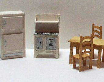 May include: A miniature dollhouse kitchen set with a white refrigerator, stove, and table with two chairs.