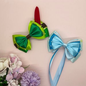 May include: Two handmade hair bows, one green with a red feather accent and one blue with a white and silver glitter accent.