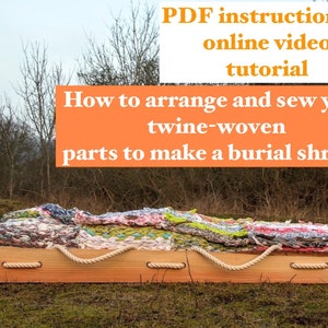May include: A wooden box with rope handles, containing a colorful woven fabric shroud. The box is sitting on a grassy field. The text "PDF instructions & online video tutorial How to arrange and sew your twine-woven parts to make a burial shroud" is displayed above the box.