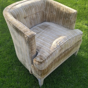 May include: A brown and white striped armchair with a curved back and a tufted seat. The chair is sitting on a green lawn.