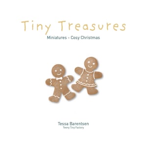 Op de afbeelding: Een boekomslag met de titel Tiny Treasures Miniatures - Cosy Christmas door Tessa Barentsen Teeny Tiny Factory. De omslag toont twee bruine peperkoekfiguurtjes met witte glazuurdetails, één met een strikje en de andere met een rokje.