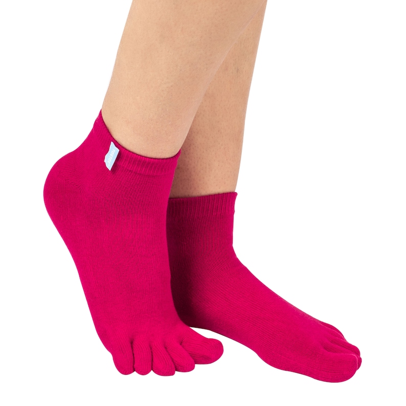 May include: A pair of vibrant fuchsia toe socks. The socks are ankle-length with individual toe compartments. A small, light blue tag is attached to the cuff of one sock. The socks are made of a soft, knitted material.
