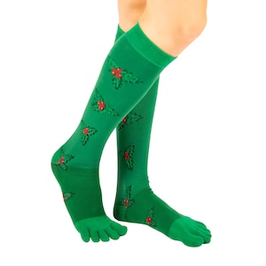 May include: Green knee-high socks with a holly berry pattern. The socks have a toe separator design and feature a repeating pattern of green holly leaves and red berries. The socks are made of a soft, stretchy material.