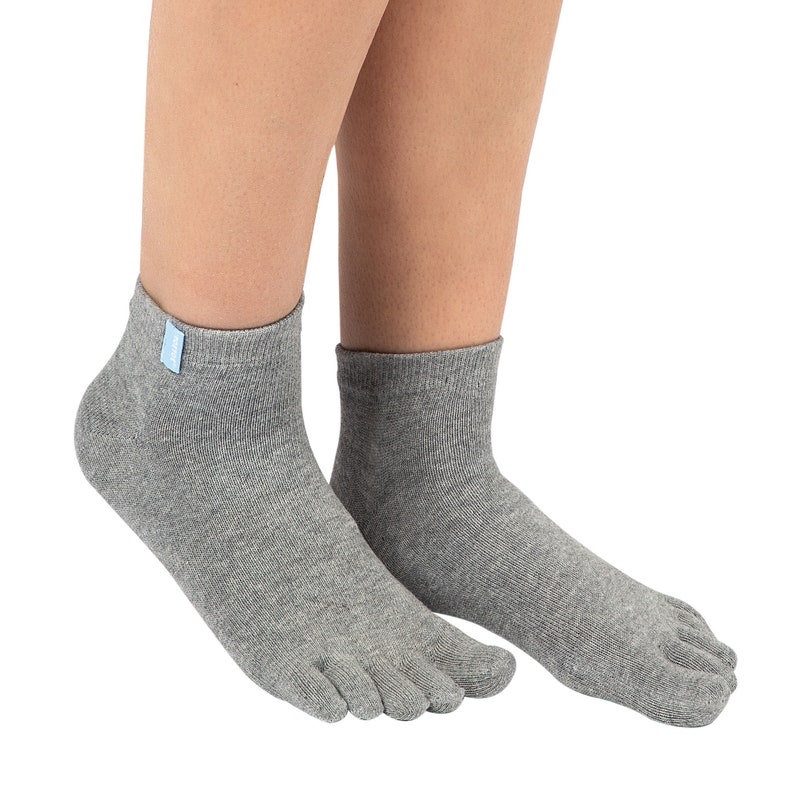 May include: Gray toe socks with a short ankle length. The socks have a separate compartment for each toe. A small blue tag is attached to the top of the sock. The socks are made of a soft, knitted material.