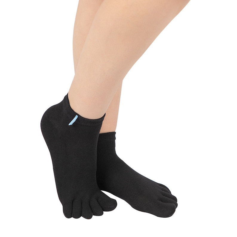 May include: Black toe socks with a light blue tag. The socks have individual toe slots and are made of a ribbed knit material. The socks are ankle-length and are worn on a person's feet.