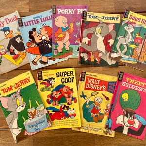 May include: A collection of vintage comic books featuring classic cartoon characters like Daffy Duck, Bugs Bunny, Tom and Jerry, and Super Goof. The covers are brightly colored with various illustrations and text, including "Happy Birthday Tom".
