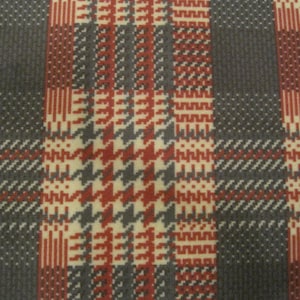 Pode incluir: Close-up de um tecido xadrez vermelho, branco e cinza com um padrão de pata de galo. O tecido é tecido com uma superfície texturizada.