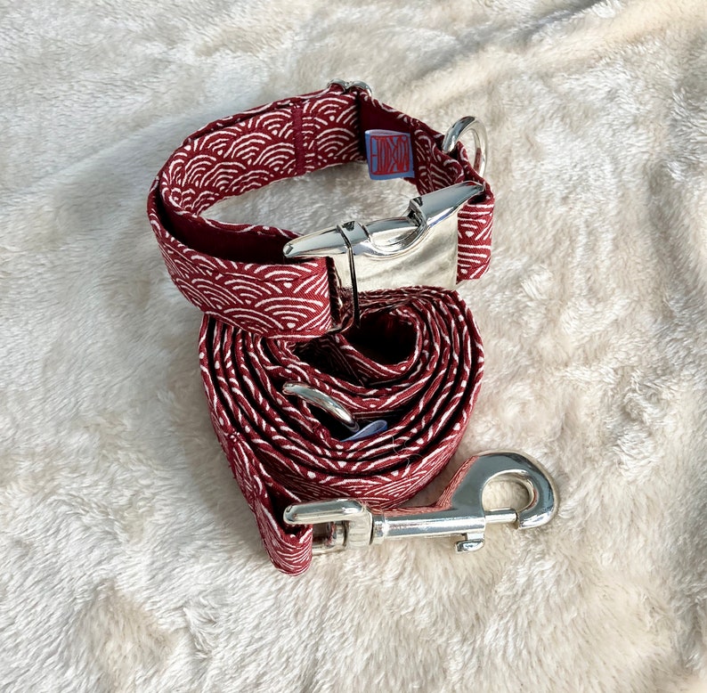 Pu&ograve; includere: Un set di collare e guinzaglio per cani bordeaux con un motivo a onde bianche. Il set include una fibbia e un moschettone in metallo argentato. Il collare ha una piccola etichetta con le lettere "HKCH".