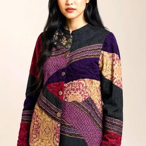 May include: A patchwork jacket in a variety of colors, including black, purple, burgundy, and gold. The jacket features a mandarin collar and gold-colored buttons. The fabric has a quilted texture and ornate patterns.