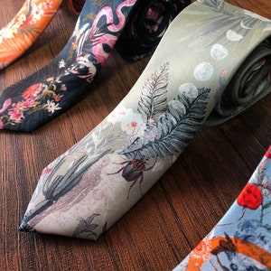 May include: Four patterned neckties, one orange with white flowers, one dark blue with pink flowers and a snake, one light green with a beetle and a fern, and one light blue with red flowers and a bird