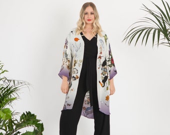 May include: A white and purple floral print kimono with a black jumpsuit underneath. The kimono has a gradient design with a white top and a purple bottom. The jumpsuit has a V-neck and a wide leg.