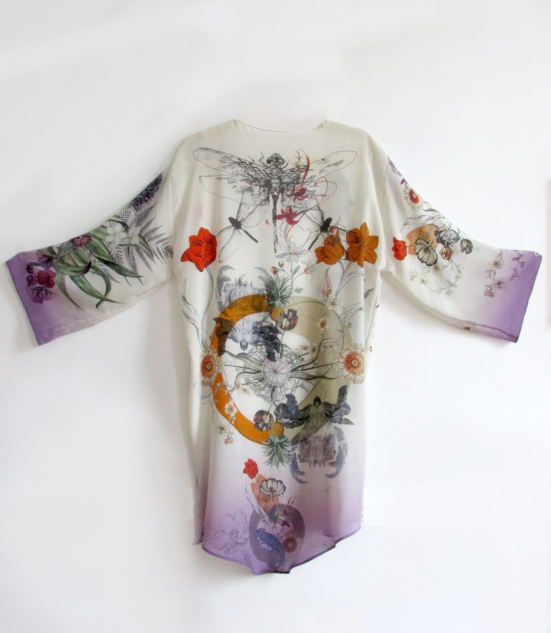 May include: A white kimono-style robe with a floral and dragonfly print. The robe features a gradient from white to purple at the hem and sleeve edges. The design includes orange and red flowers, and a circular graphic.