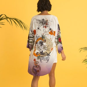 May include: A white kimono-style robe with a colorful floral and insect design. The robe has long sleeves and a purple ombre effect at the hem. The design includes orange, red, and green elements.
