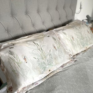 May include: A white bed with a gray headboard and a white duvet cover with a floral pattern. Two white pillows with a floral pattern are on the bed.