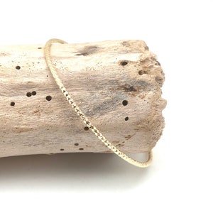 May include: A gold bangle bracelet with a textured diamond pattern.