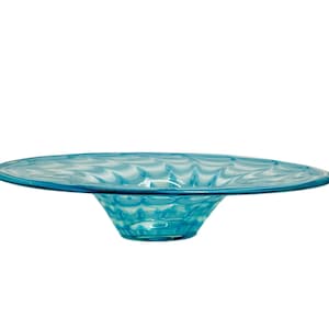 May include: A large, light blue glass bowl with a wavy, textured design. The bowl is wide and shallow, with a slightly flared rim.