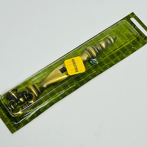 May include: A gold-toned metal door handle with a decorative design. The handle is packaged in a clear plastic bag with a yellow label that reads "REVELSTOKE".
