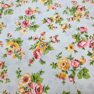 Puede incluir: Una tela blanca con un patr&oacute;n floral. Las flores son rosas y amarillas con hojas verdes.
