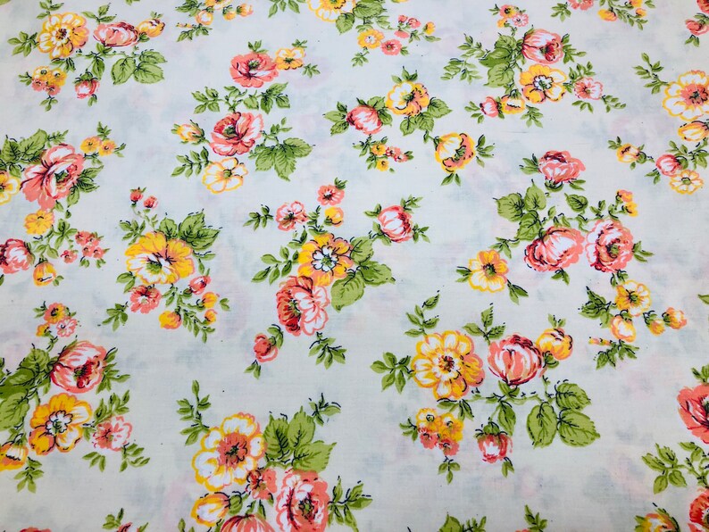 Puede incluir: Una tela blanca con un patr&oacute;n floral. Las flores son rosas y amarillas con hojas verdes.