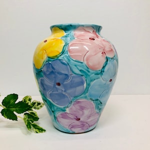May include: A blue ceramic vase with a floral design. The vase is decorated with pink, yellow, and blue flowers.