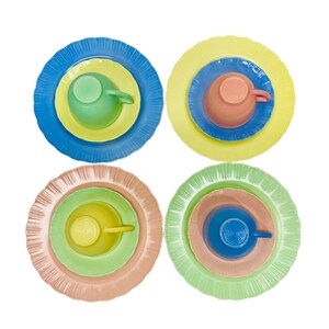 May include: Four sets of colourful dishware, each with a unique arrangement. Each set includes a large plate, a smaller plate, and a cup. The colour schemes include blue, yellow, green, and peach, creating a vibrant and playful aesthetic.