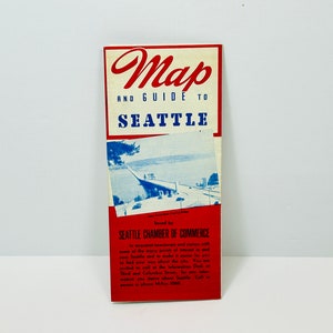 Puede incluir: Un mapa y guía vintage de Seattle, Washington, en rojo, blanco y azul. El mapa está publicado por la Cámara de Comercio de Seattle. La imagen muestra un puente sobre el agua con un coche conduciendo por él.