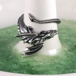 May include: A silver dragon ring with a detailed design. The dragon's tail wraps around the ring band.
